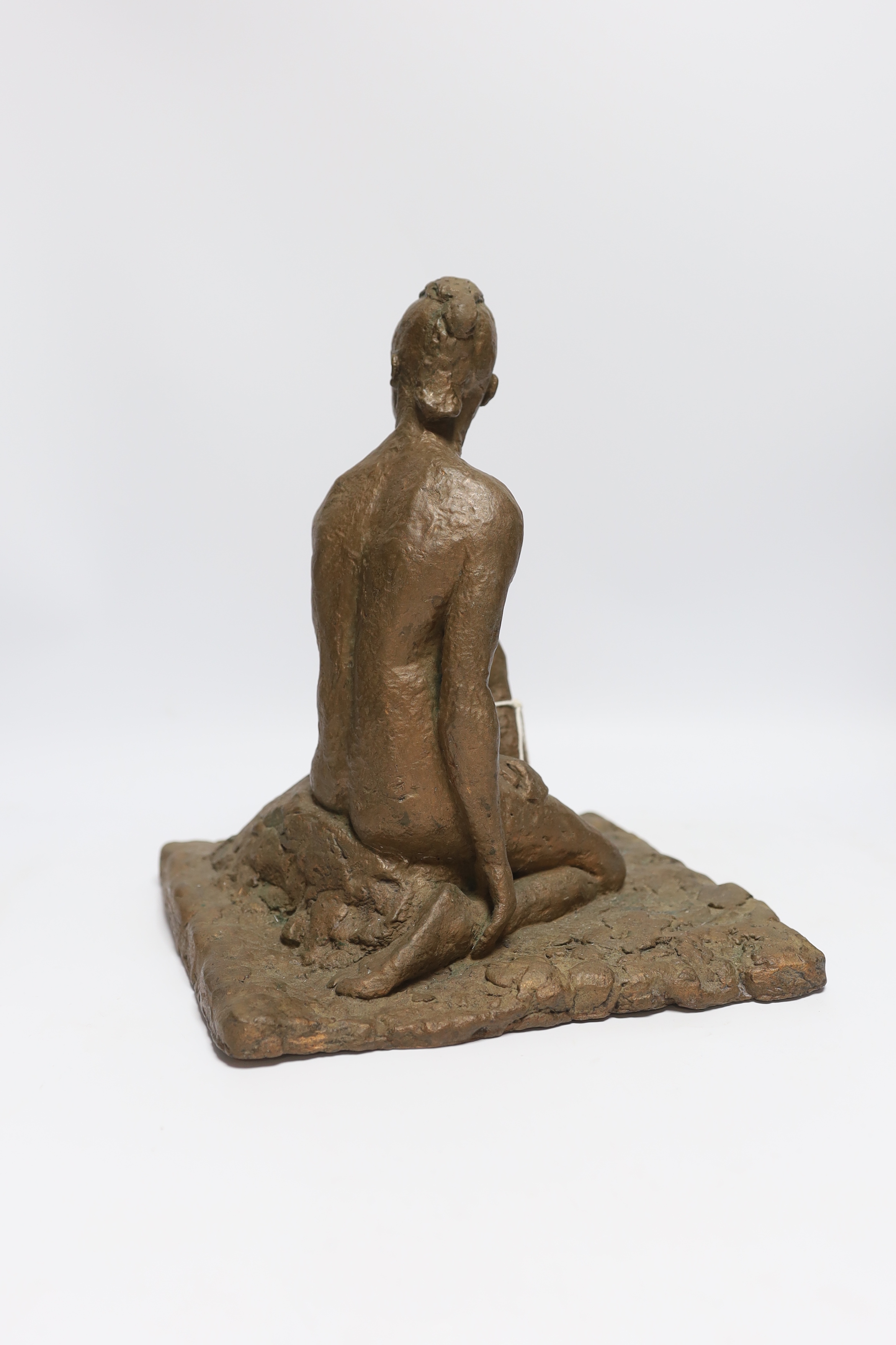 An abstract bronzed resin sculpture of a kneeling man, 30cm